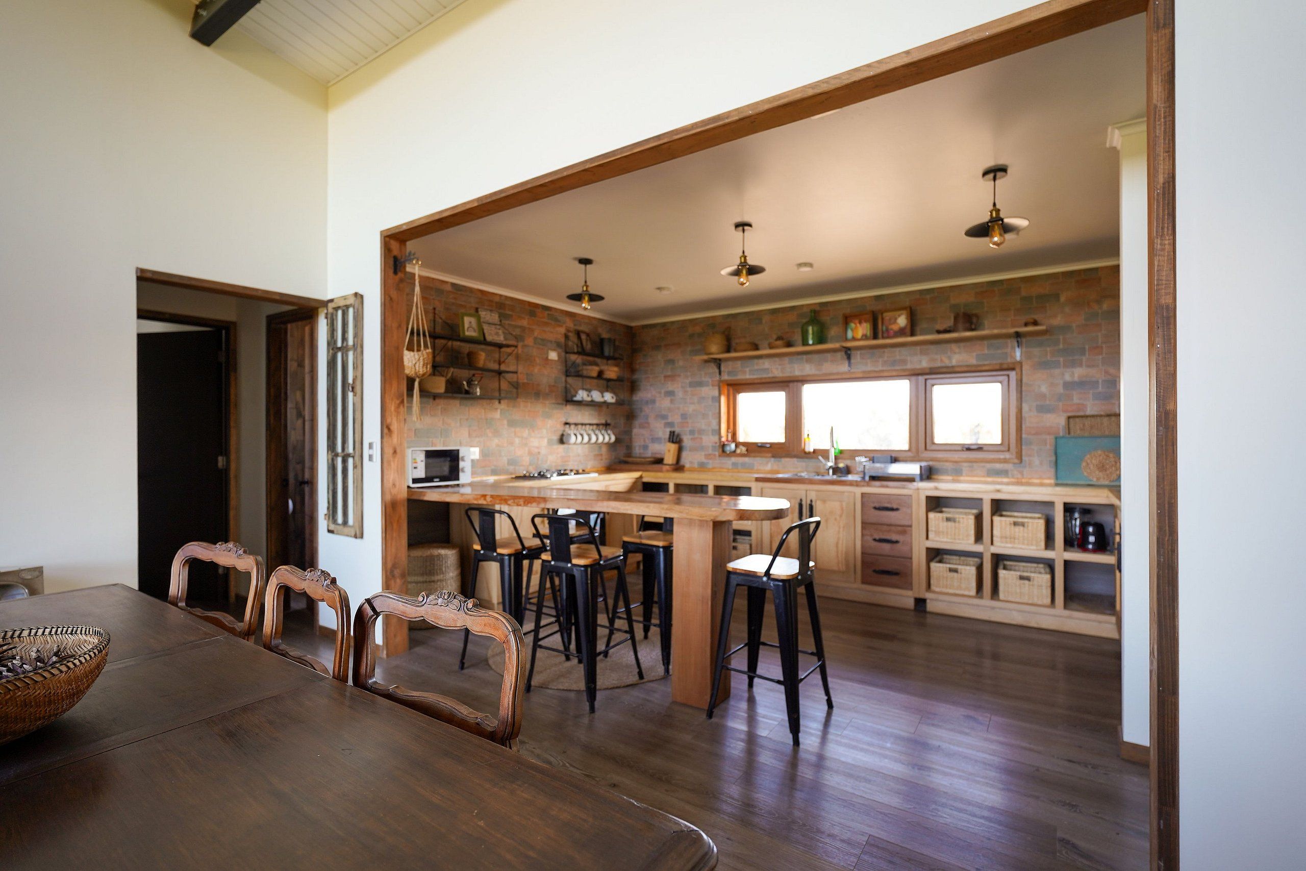 Cocina amplia con una isla central, sillas de madera y una mesa de comedor con una cesta de mimbre.
