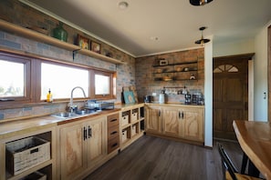 A kitchen with wooden cabinets, a built-in oven, and a window. - Oceana Suites Altos de Neoalerce (Puerto Montt)