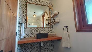 A bathroom with a mirror, a sink, a towel rack, and patterned tiles.