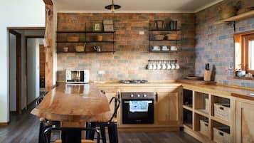 A kitchen with a brick backsplash, wooden cabinets, and a central island with chairs.