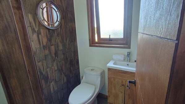 A bathroom with a wooden floor, a toilet, a sink, and a window. - Oceana Suites Altos de Neoalerce (Puerto Montt)