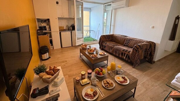 A modern living room with a dining area, a sofa, and a kitchen in the background. - Perle de Carnon Plage (Mauguio)
