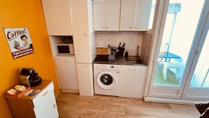 A compact kitchen with a washing machine, a coffee machine, and a small refrigerator. - Perle de Carnon Plage (Mauguio)