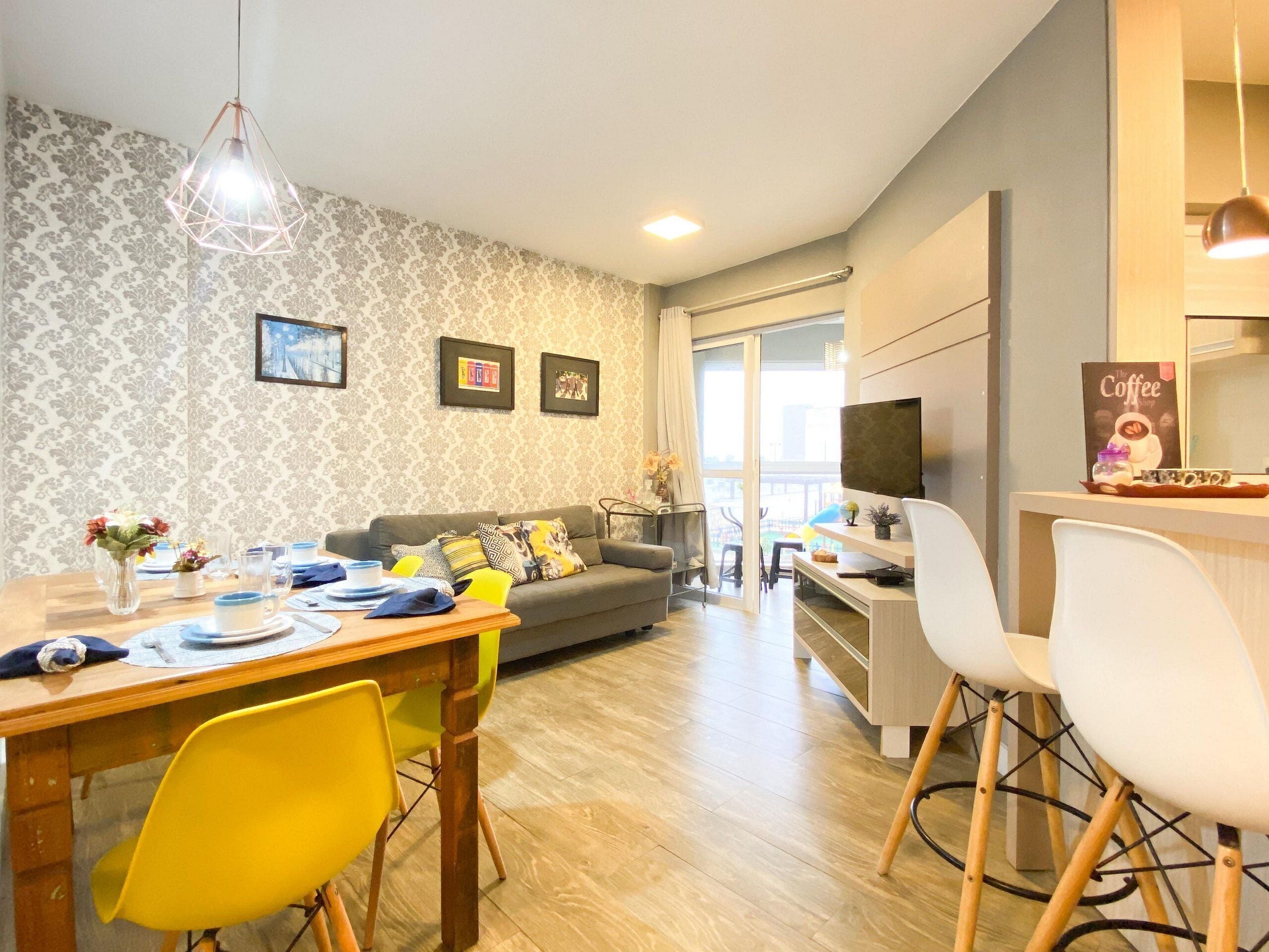 Una sala moderna con comedor, sofá, televisor y estación de café.