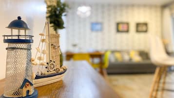 Ein Modellschiff mit Leuchtturm und Segelboot auf einer Holztischplatte.
