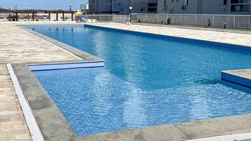 Una piscina rectangular con borde de azulejos, rodeada por una terraza de piedra.