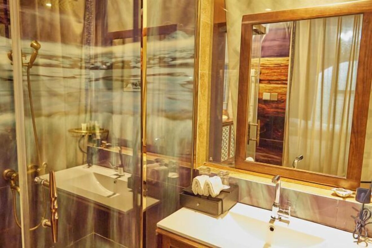 A bathroom with a glass shower enclosure, a sink, and a mirror with a wooden frame.