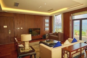 A spacious living room with a large flat-screen TV, comfortable seating, and a view of the outdoors. - Heceng Qiyuan Art Hotel (Dali City)