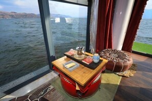 A room with a view of the sea, a small table with a book and a cup, and a red ottoman. - Heceng Qiyuan Art Hotel (Dali City)