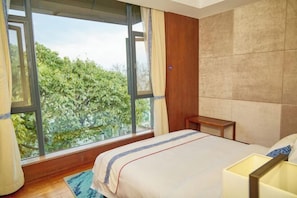 A bedroom with a large window, a bed, a bedside table, and a nightstand. - Heceng Qiyuan Art Hotel (Dali City)