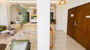 Un hall d’hôtel comprenant un comptoir d’accueil, un espace salon avec un tapis à motifs et une armoire en bois.