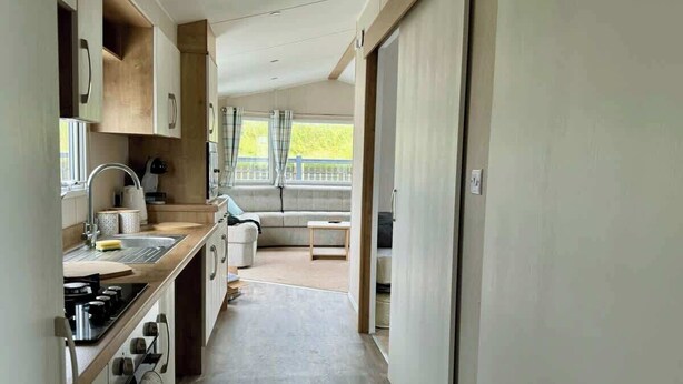 Una cocina moderna con una isla central, un rincón de comedor con sofá y vistas a través de un ventanal corredero.