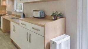 Una cocina moderna con armarios blancos, horno integrado y radiador blanco.