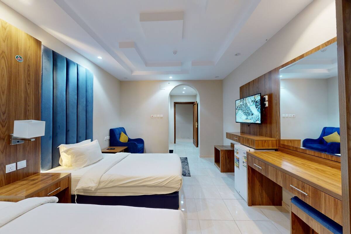 Une chambre d’hôtel avec deux lits, une télévision, un bureau et un miroir.