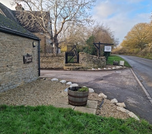 A rural setting with a stone wall, a sign for 'Diamond Farm,' a gated entrance, and a road leading to a park.