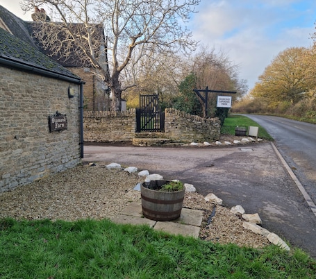 A rural setting with a stone wall, a sign for 'Diamond Farm,' a gated entrance, and a road leading to a park.. Cosy two bedroom countryside apartment. Close to major attractions. Dog Friendly