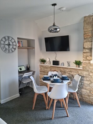 A modern dining area with a stone accent wall, a flat-screen TV, and a minimalist decor. - Cosy two bedroom countryside apartment. Close to major attractions. Dog Friendly (Bletchingdon)