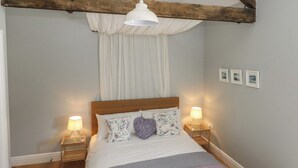 A bedroom with a wooden ceiling, a bed with white bedding, two bedside lamps, and a hanging light fixture. - Tothery (Beaminster)