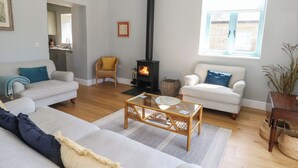 A living room with a fireplace, two sofas, a coffee table, and a window. - Tothery (Beaminster)