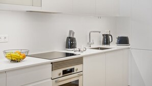 A modern kitchen with white cabinetry, a stainless steel sink, a Bosch microwave, a toaster, and a kettle. - Acqua s Bliss by Homie (Funchal)