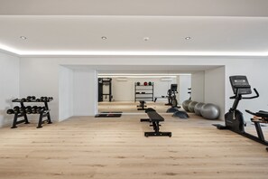 A modern gym with wooden flooring, various exercise equipment, and a bench.