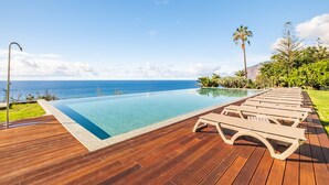 A wooden deck with a pool and lounge chairs overlooking the ocean. - Acqua s Bliss by Homie (Funchal)