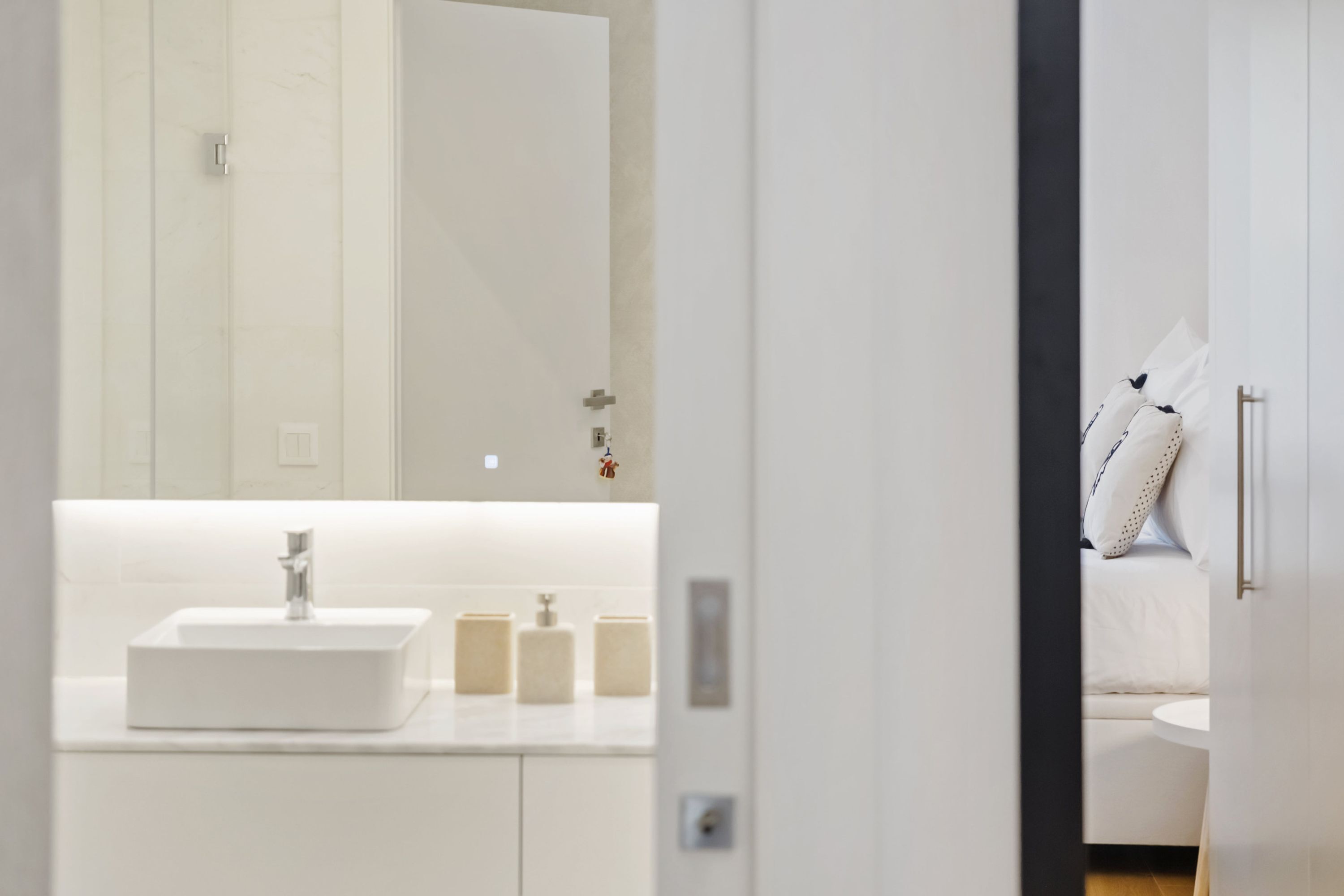 A modern bathroom with a white sink, mirror, and storage cabinets.