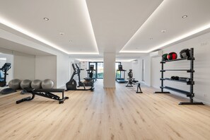 Ein modernes Fitnessstudio mit Trainingsgeräten, Holzboden und einem großen Fenster.