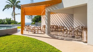 An outdoor patio with wooden furniture and a pool, surrounded by a well-maintained lawn and palm trees. - Acqua s Bliss by Homie (Funchal)