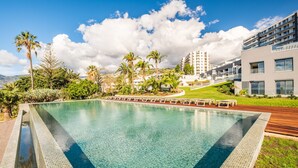 A large swimming pool with a tiled edge, surrounded by palm trees and a grassy area. - Acqua s Bliss by Homie (Funchal)