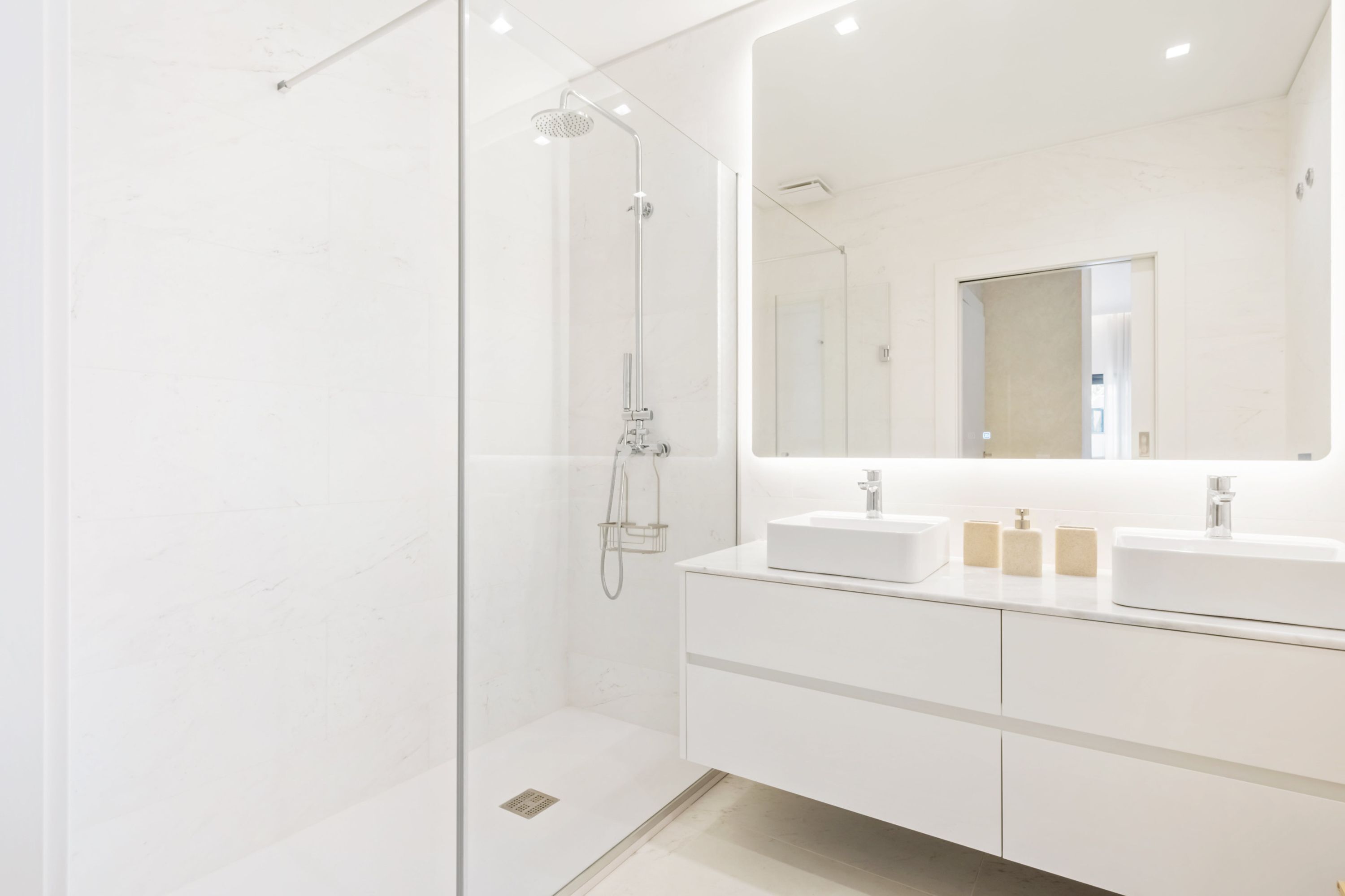 A modern bathroom with a glass-enclosed shower, a large mirror, and a white vanity with two sinks.