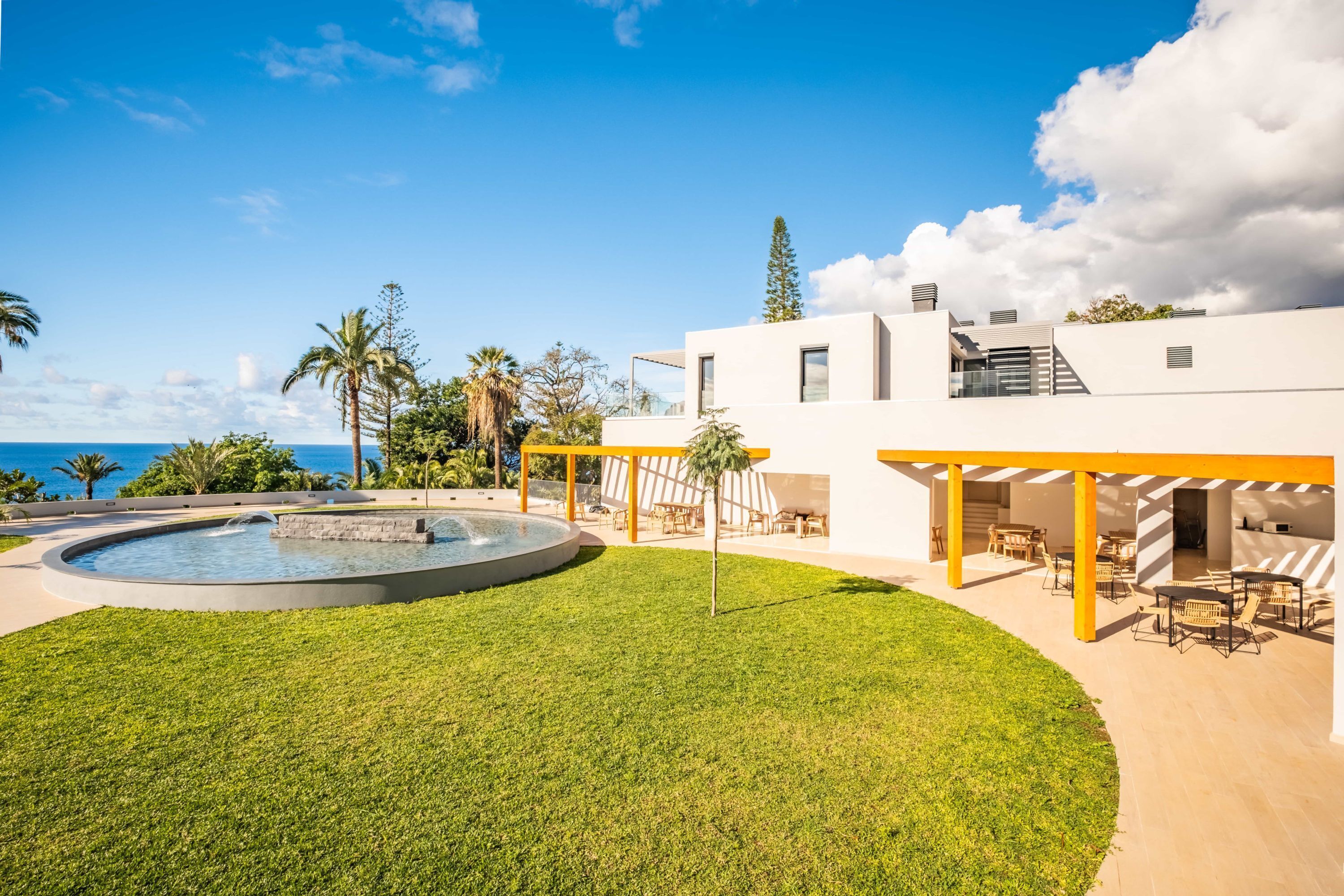A modern outdoor patio area with a pool, seating, and a view of the ocean.