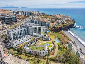A coastal residential area with modern buildings, a beach, and a large swimming pool. - Acqua s Bliss by Homie (Funchal)