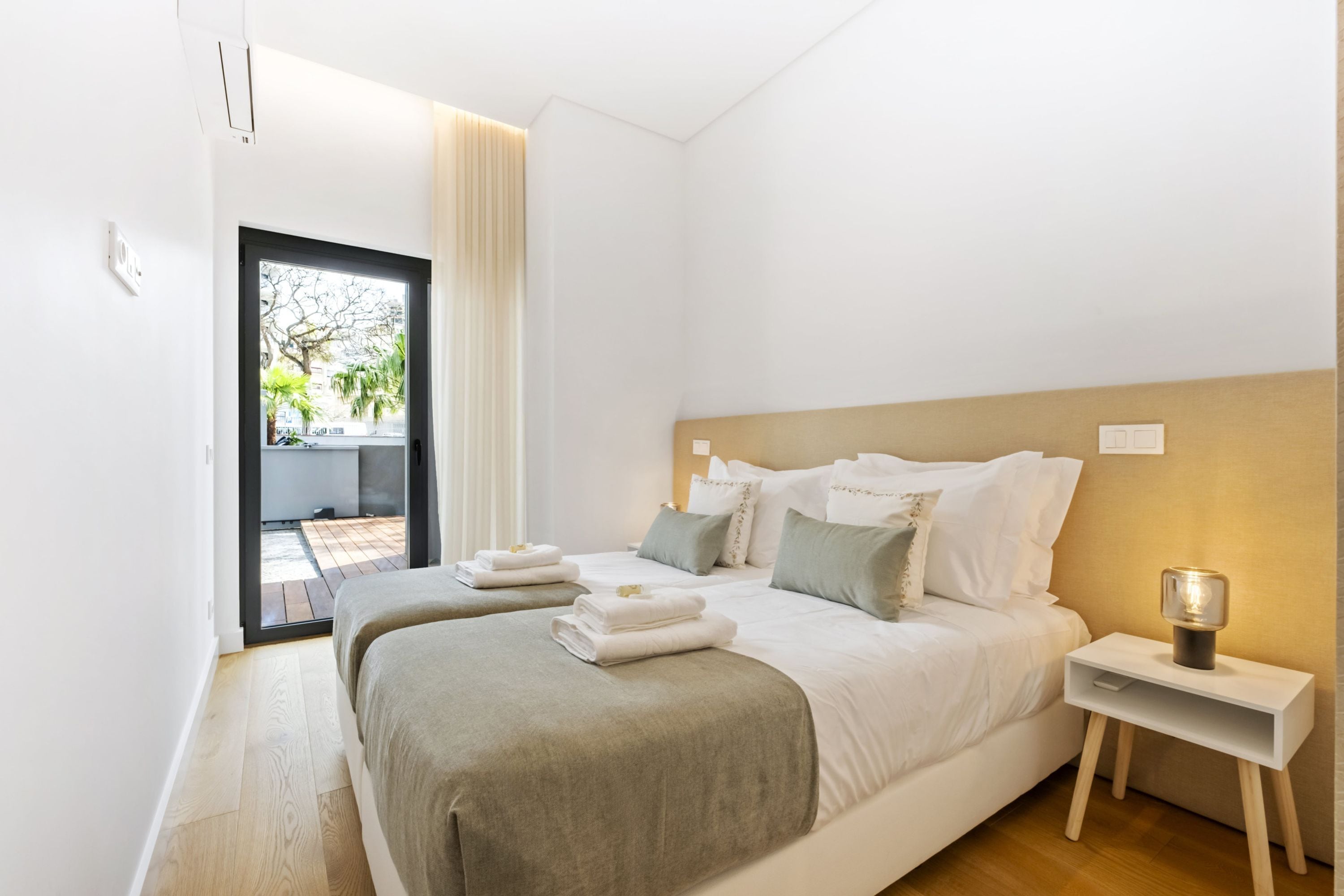 Un dormitorio moderno con una cama grande, una mesita de noche y vistas al exterior.
