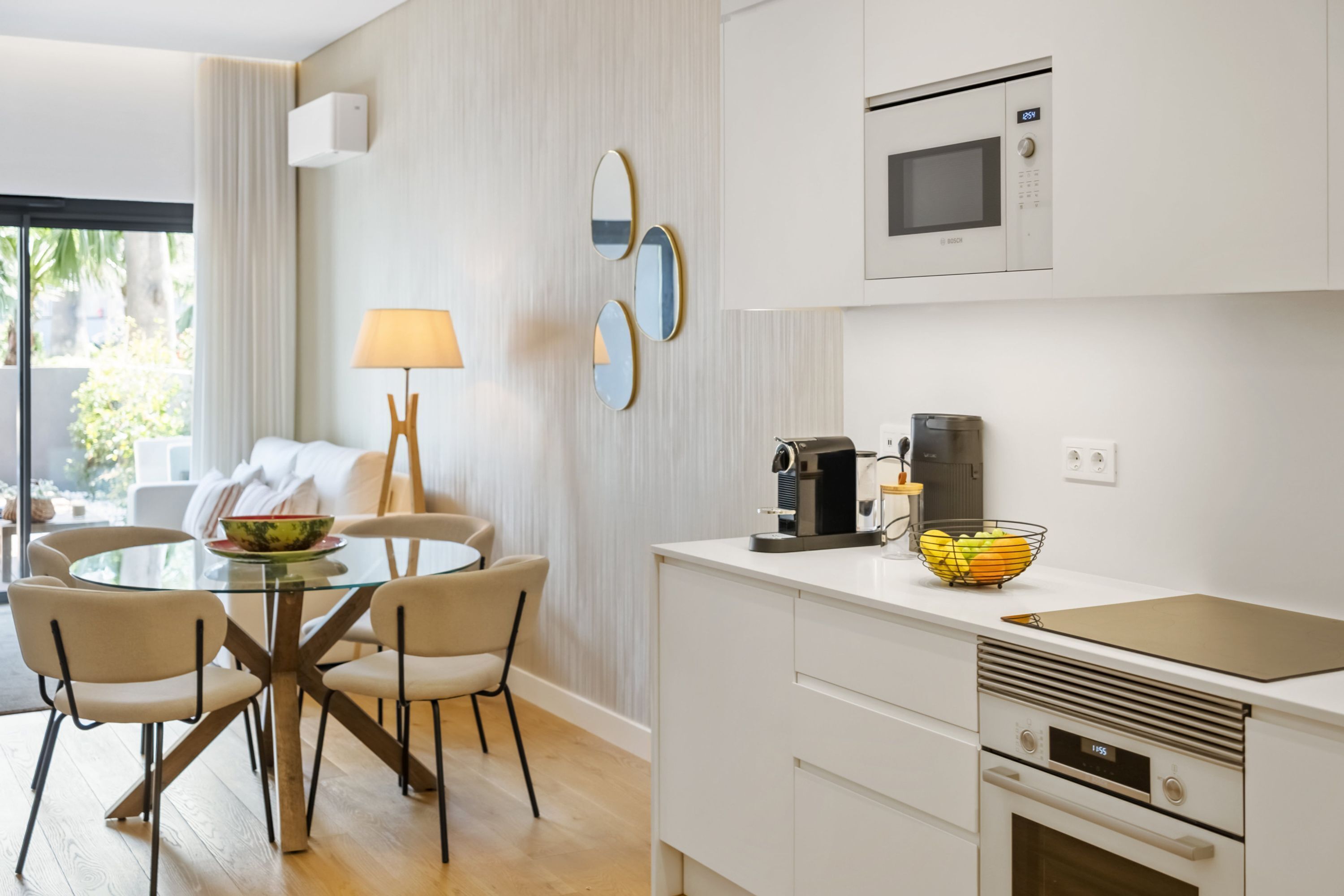 A modern kitchen with a microwave, coffee maker, and a bowl of fruit on the counter.