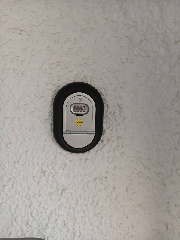 A Yale deadbolt lock on a textured white wall.