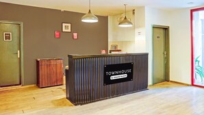 Una mesa de recepción con la etiqueta 'TOWNHOUSE' y un cartel de la empresa, suelo de madera y dos puertas.