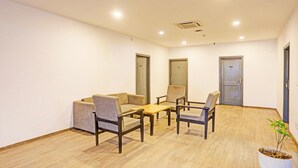 Un salón de conferencias con una mesa de madera, cuatro sillas, un sofá y una planta en maceta.