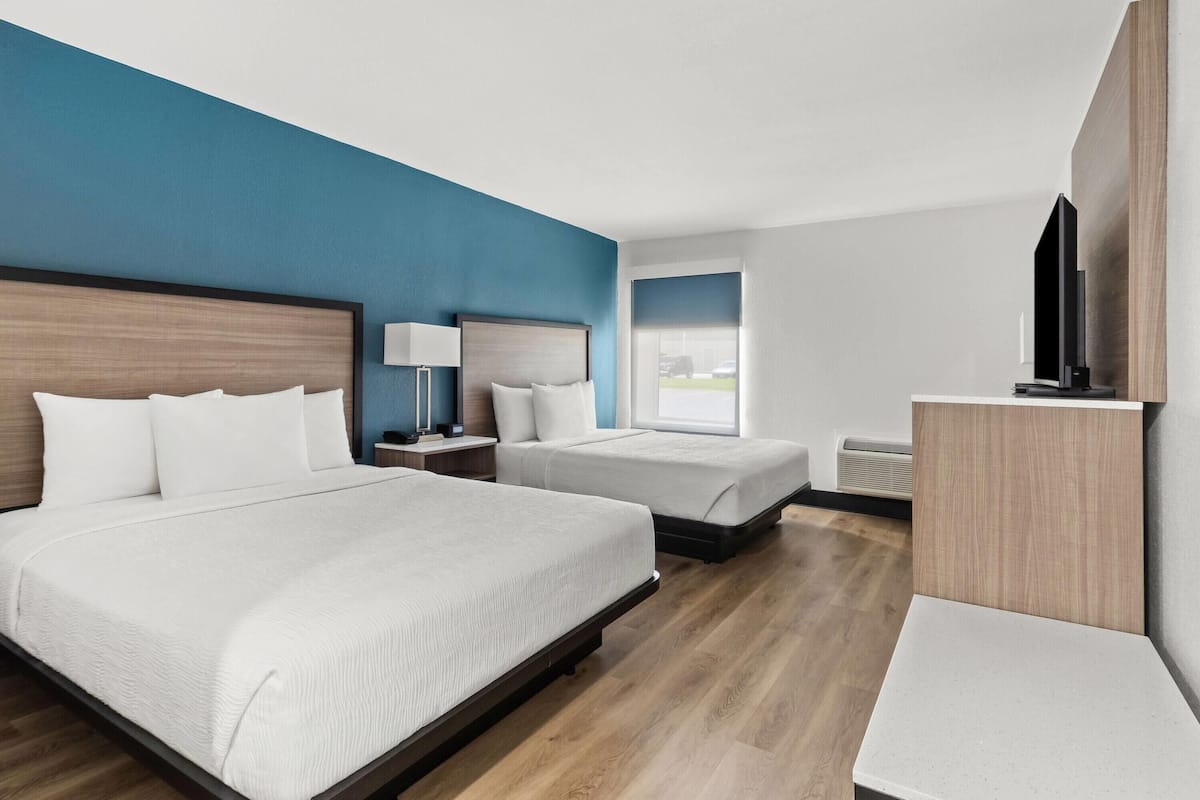 Habitación de hotel con dos camas, un televisor y un escritorio.