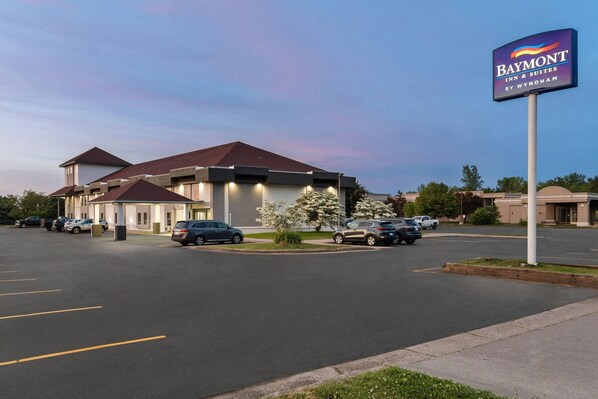 A Baymont Inn & Suites by Wyndham with a parking lot and a building with a red roof. - Baymont by Wyndham Batavia - Darien Lake (Batavia)