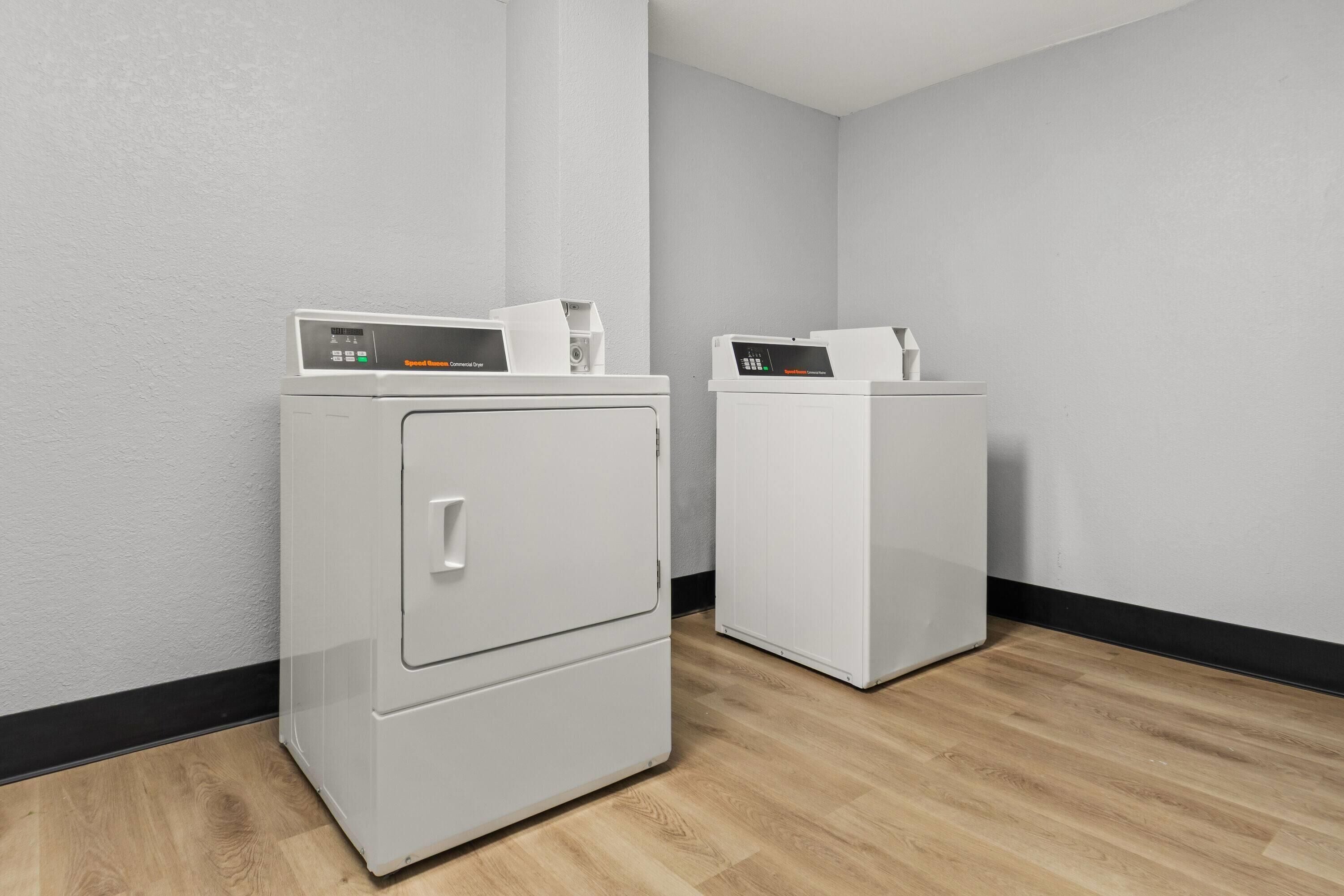 A laundry room with two white front-loading washing machines and a dryer.