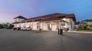 A modern hotel with a covered parking area and multiple cars parked outside.