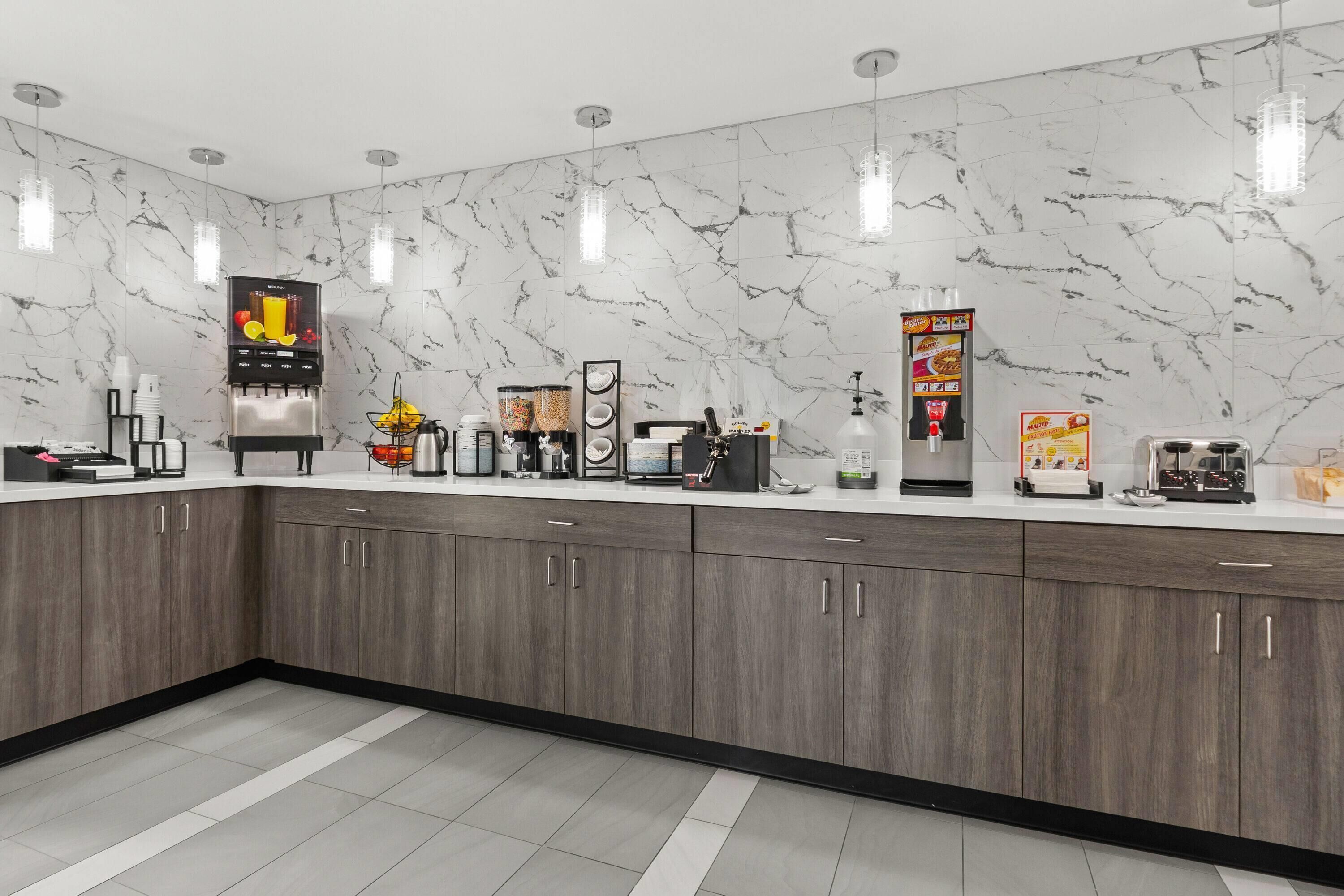 A modern kitchen with marble backsplash, built-in appliances, and a coffee station.