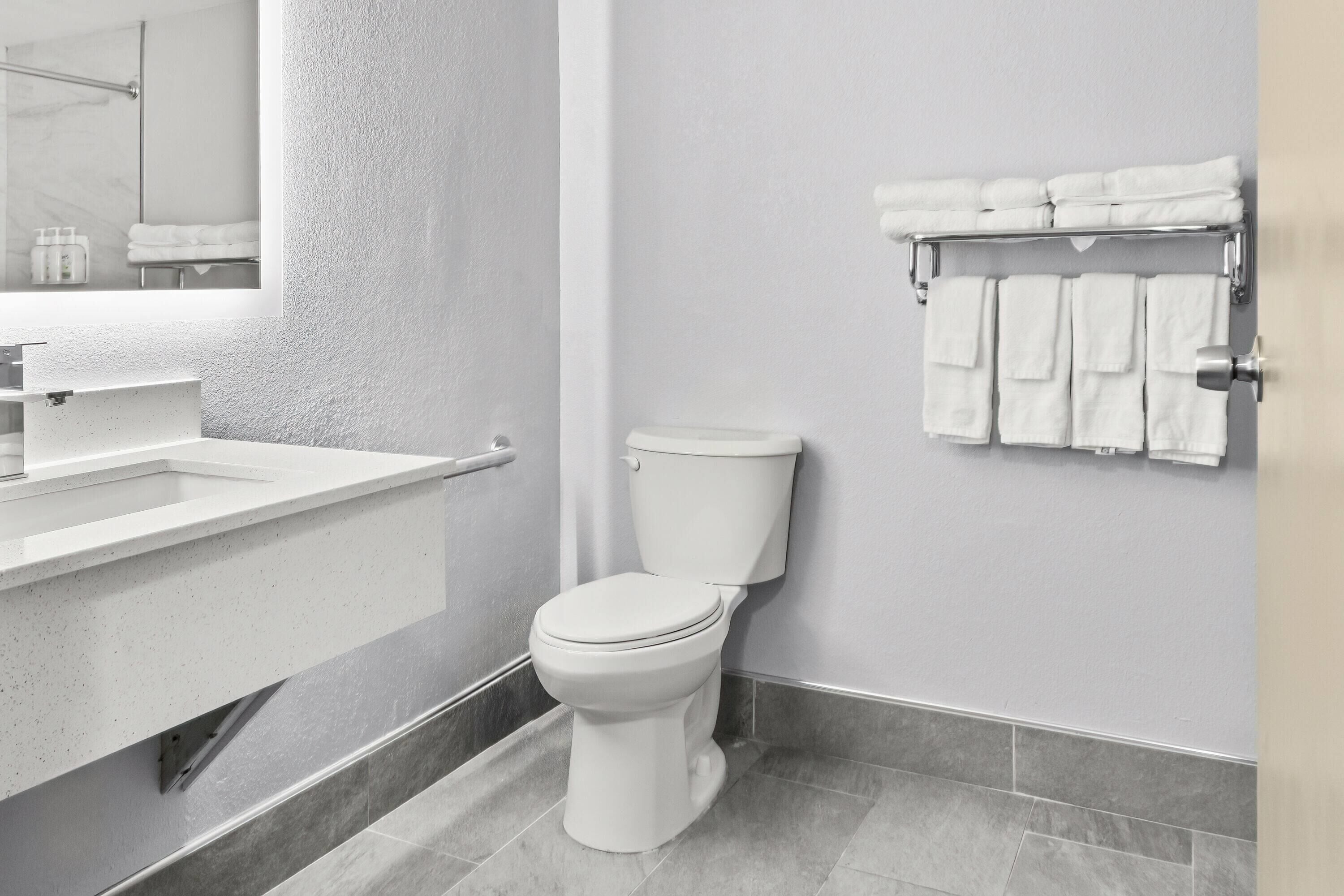 A modern bathroom with a white toilet, a sink, and a towel rack.