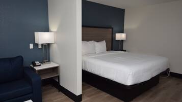 Habitación de hotel con cama, lámparas de noche, escritorio con teléfono y sofá azul.