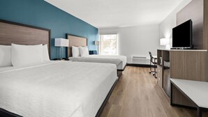 A hotel room with two beds, a TV, a desk, and a chair.