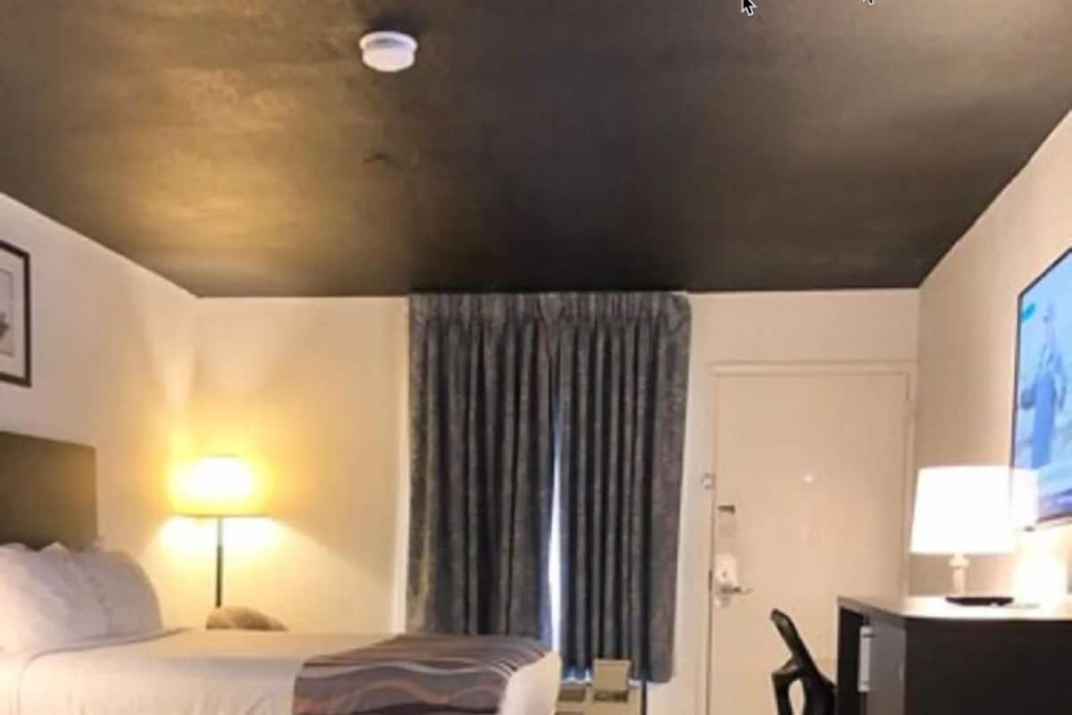 Camera d'albergo con due letti, una scrivania, una sedia, una televisione e una lampada.