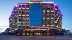 Un hôtel à plusieurs étages, doté d’une enseigne bien visible indiquant « RAMADA BY WYNDHAM » et d’une grande façade bleue.