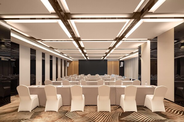 A conference room with rows of white chairs, a large screen at the front, and modern lighting fixtures. - Wyndham Changsha Yanghu (Changsha)