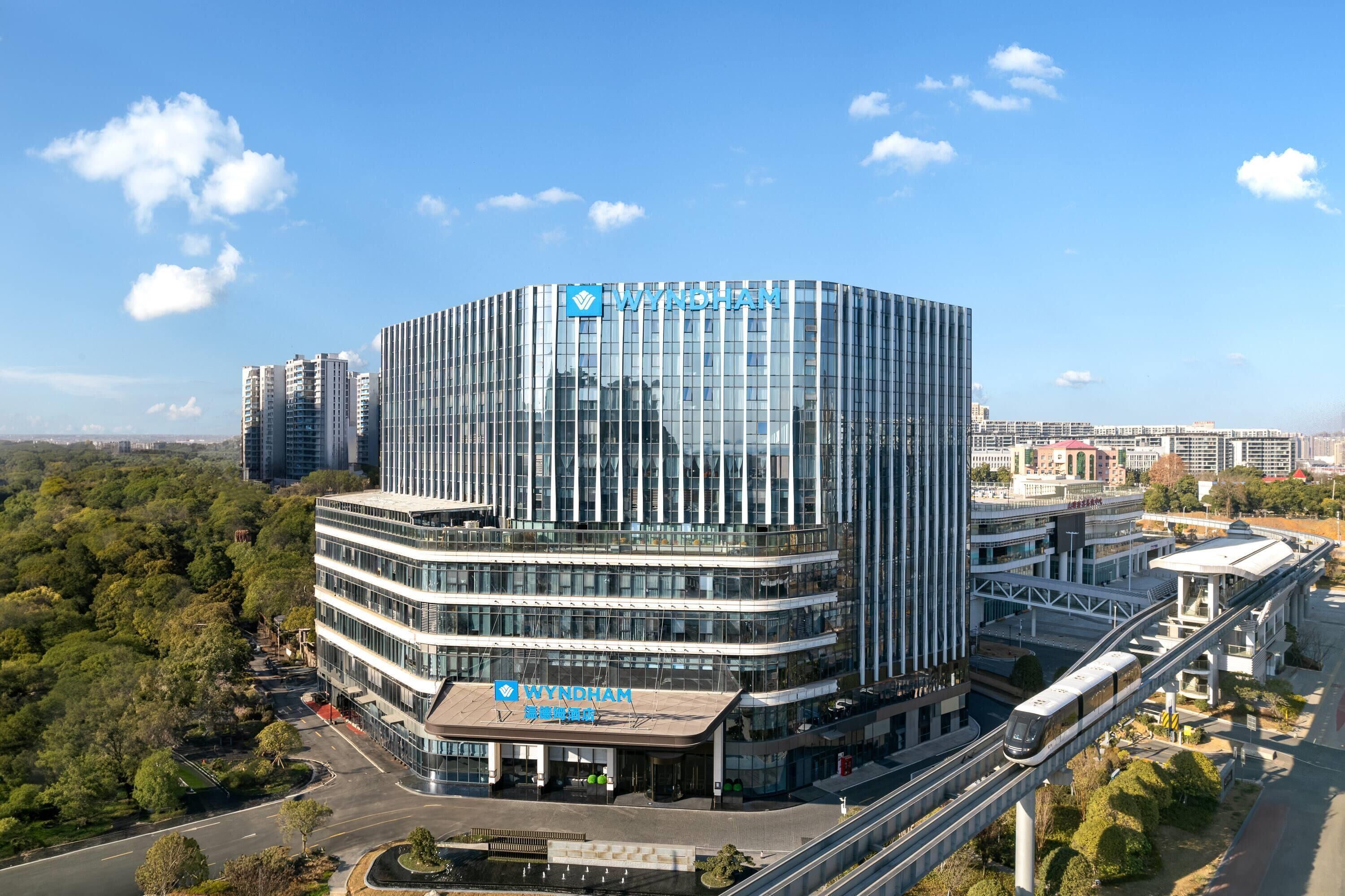 A modern building with the name 'WYNDHAM' prominently displayed, featuring a curved glass facade and a multi-level structure.